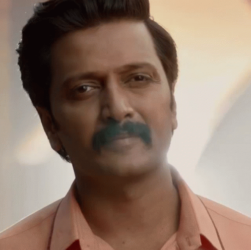 A Close Up Of A Man With A Mustache Wearing A Pink Shirt GIF