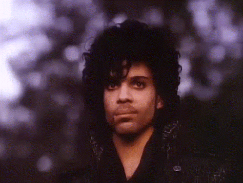 A Close Up Of A Man With Curly Hair And Purple Eyes GIF
