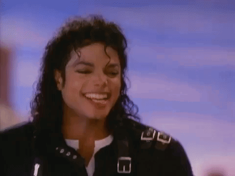 A Close Up Of A Man With Curly Hair Smiling In Front Of A Blue Sky . GIF