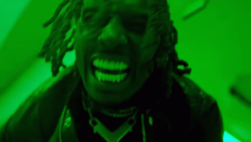 A Close Up Of A Man With Dreadlocks Smiling In A Green Room . GIF