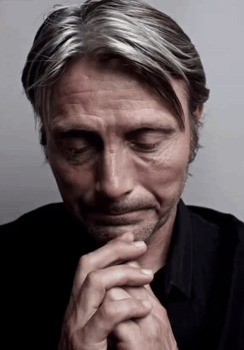 A Close Up Of A Man With His Eyes Closed And His Hands Folded GIF