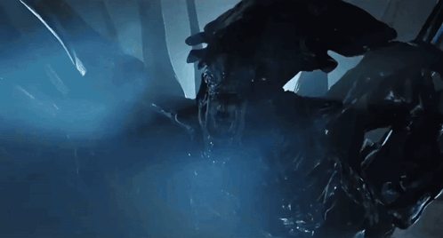 a close up of a monster in a dark room with a blue light behind it