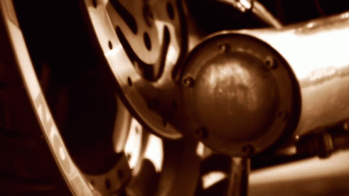 A Close Up Of A Motorcycle Wheel With A Exhaust Pipe In The Foreground GIF