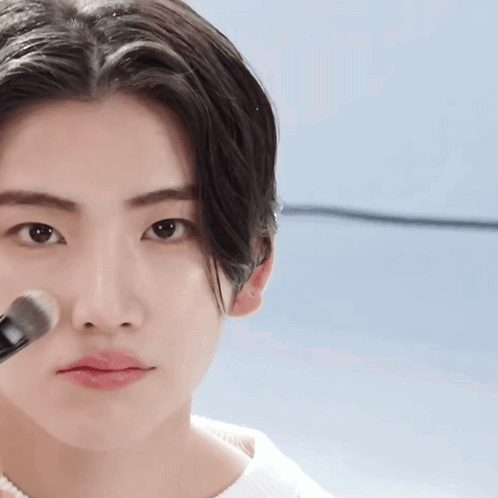 A Close Up Of A Person Applying Makeup With A Brush On Their Face GIF