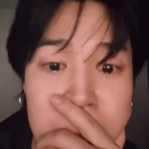 A Close Up Of A Person Covering Their Face With Their Finger . GIF