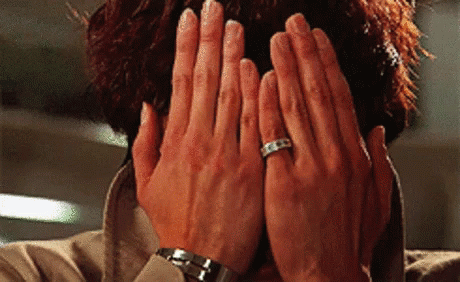 A Close Up Of A Person Covering Their Face With Their Hands And A Ring On Their Finger . GIF