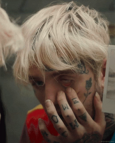 A Close Up Of A Person Covering Their Face With Their Hands With A Tattoo On Their Finger That Says ' A ' GIF