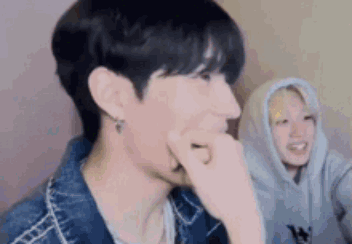 A Close Up Of A Person Covering Their Mouth With Their Hand While Another Person Looks On . GIF