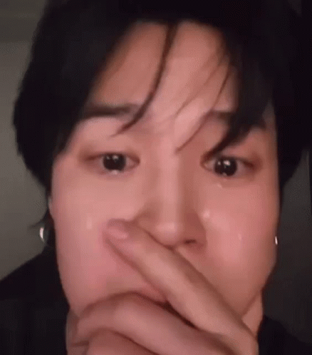 A Close Up Of A Person Covering Their Mouth With Their Hand While Crying . GIF