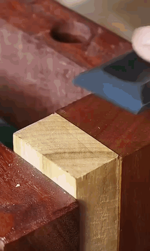 a close up of a person cutting a piece of wood with a hammer .