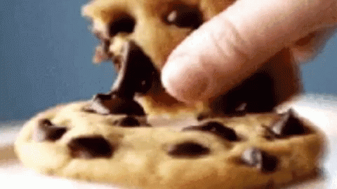 A Close Up Of A Person Eating A Chocolate Chip Cookie With Their Finger . GIF