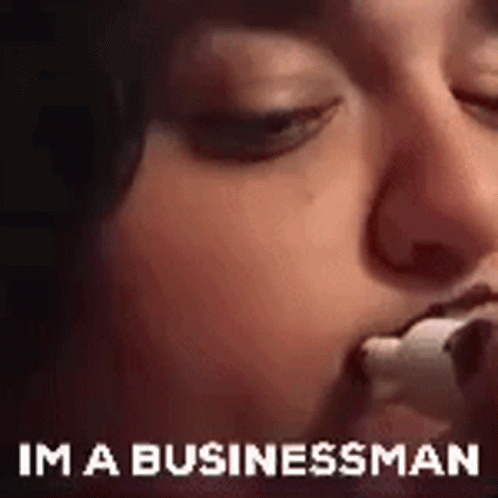 A Close Up Of A Person Eating A Marshmallow With The Words `` Im A Businessman '' Written Below It . GIF
