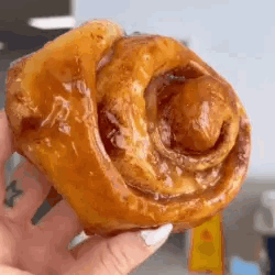 A Close Up Of A Person Holding A Cinnamon Roll . GIF