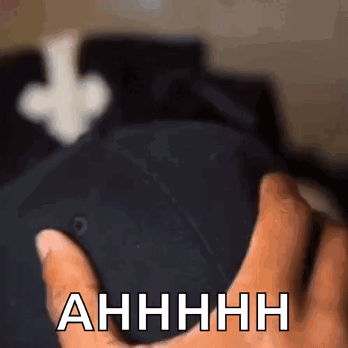 A Close Up Of A Person Holding A Hat That Says " Ahhhh " On It GIF