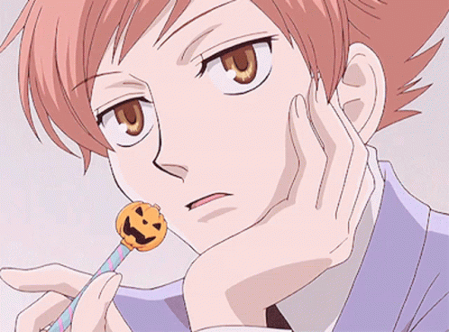 A Close Up Of A Person Holding A Lollipop With A Face On It GIF