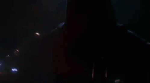 A Close Up Of A Person Holding A Red Lightsaber In A Dark Room . GIF