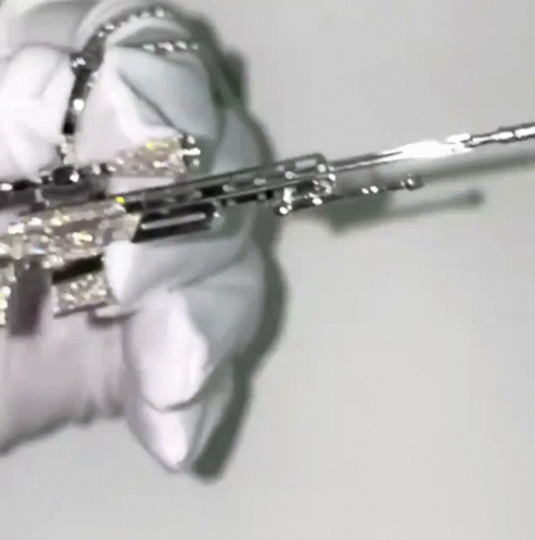 A Close Up Of A Person Holding A Silver Gun With Diamonds On It . GIF