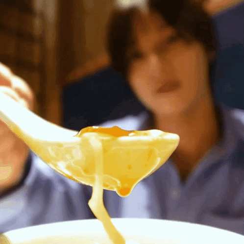 A Close Up Of A Person Holding A Spoon Full Of Soup GIF