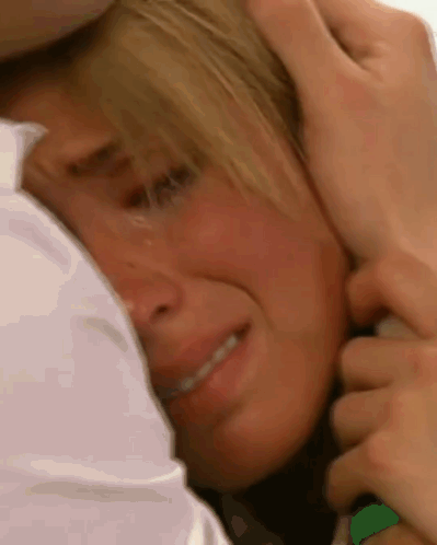 a close up of a person holding a woman 's head who is crying