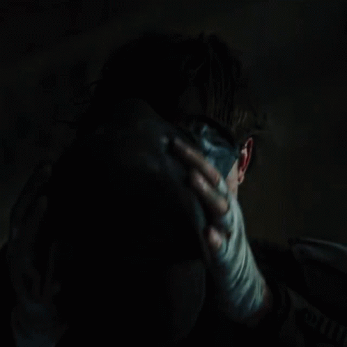 A Close Up Of A Person Holding Another Person 'S Face In A Dark Room GIF