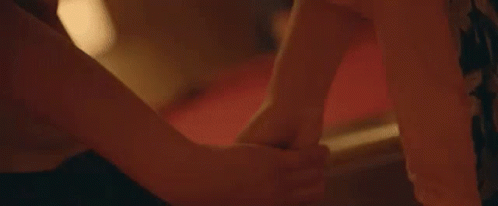 A Close Up Of A Person Holding Another Person 'S Hand While Laying On A Bed . GIF