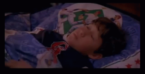 A Close Up Of A Person Laying On A Bed With A Blanket On It . GIF