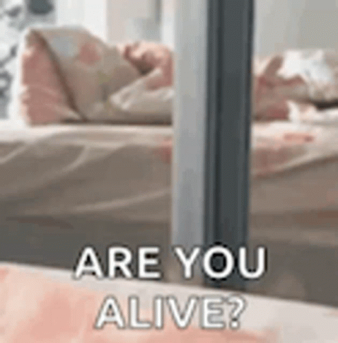 A Close Up Of A Person Laying On A Bed With The Words `` Are You Alive '' Written On It . GIF