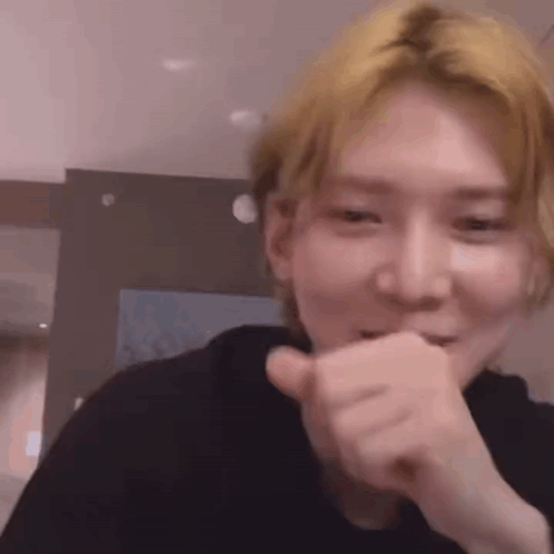 A Close Up Of A Person Making A Funny Face While Covering Their Mouth With Their Hand . GIF