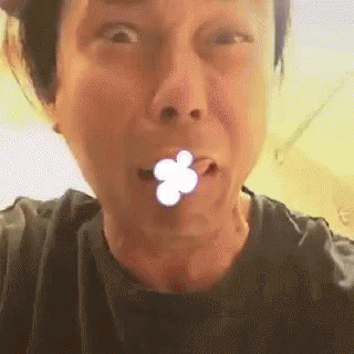 A Close Up Of A Person Making A Funny Face With A Flower In Their Mouth . GIF