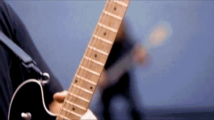 A Close Up Of A Person Playing A Guitar With A Blue Background . GIF