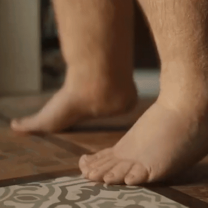 A Close Up Of A Person 'S Bare Feet On A Tile Floor . GIF