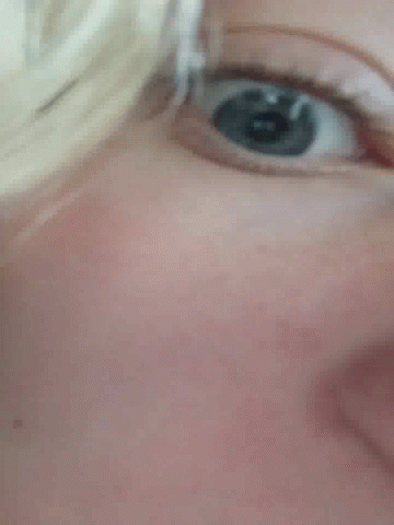 A Close Up Of A Person 'S Blue Eye With A Reflection Of A Person 'S Face . GIF