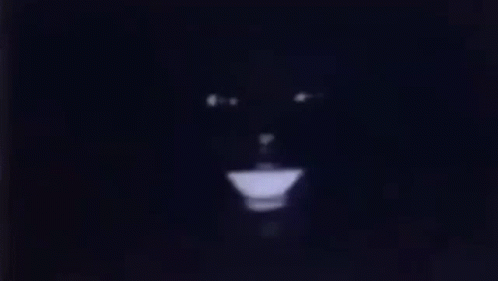 A Close Up Of A Person 'S Face In The Dark With A Light Coming Out Of It . GIF