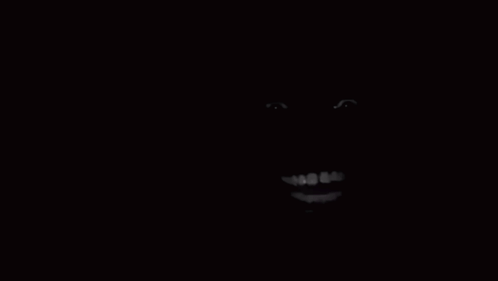 A Close Up Of A Person 'S Face In The Dark With A Smile On It . GIF