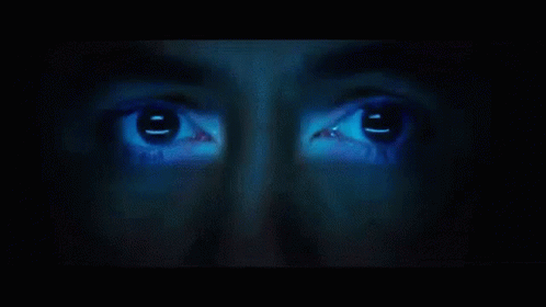 A Close Up Of A Person 'S Face With A Blue Light Shining On It GIF
