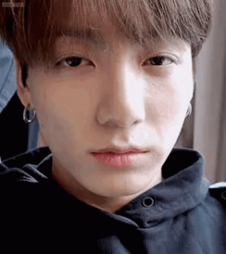A Close Up Of A Person 'S Face With A Hoodie And Earrings . GIF