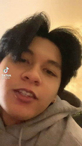 A Close Up Of A Person 'S Face With A Hoodie On And A Purple Haircut . GIF