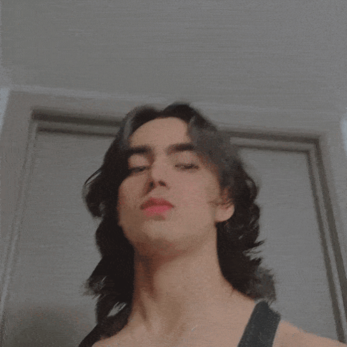 A Close Up Of A Person 'S Face With A Necklace That Says ' I ' On It GIF