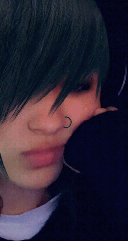 A Close Up Of A Person 'S Face With A Nose Ring And Earrings GIF