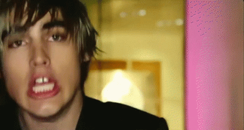 a close up of a person 's face with a pink wall in the background