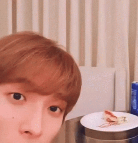 a close up of a person 's face with a plate of food on a table .