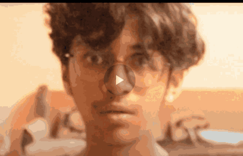 A Close Up Of A Person 'S Face With A Play Button On The Nose GIF