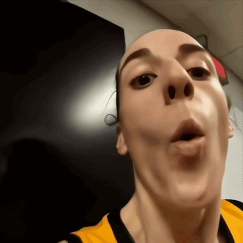 A Close Up Of A Person 'S Face With A Red Exit Sign In The Background GIF