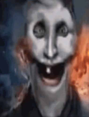 A Close Up Of A Person 'S Face With A Smiley Face And A Fire In The Background . GIF