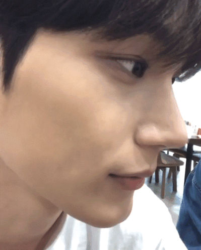 A Close Up Of A Person 'S Face With A Table And Chairs In The Background GIF