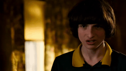 A Close Up Of A Person 'S Face With A Yellow Collar And A Black Shirt . GIF