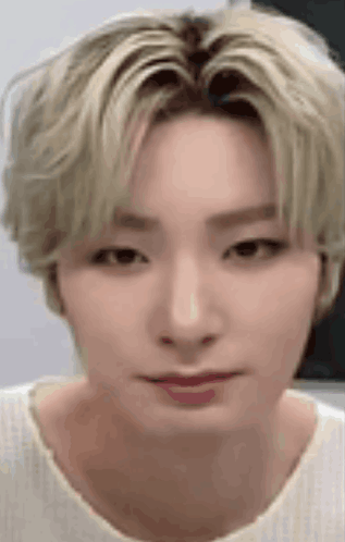 A Close Up Of A Person 'S Face With Blonde Hair And A White Shirt On . GIF