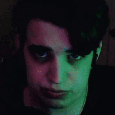 A Close Up Of A Person 'S Face With Green And Pink Lights Behind Them GIF