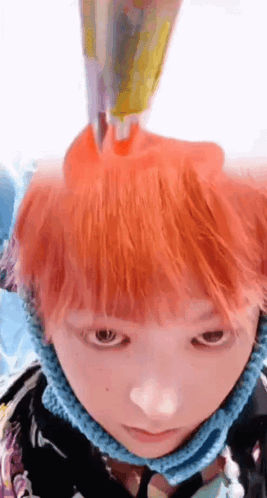 A Close Up Of A Person 'S Face With Orange Hair And A Blue Scarf Around Their Neck GIF