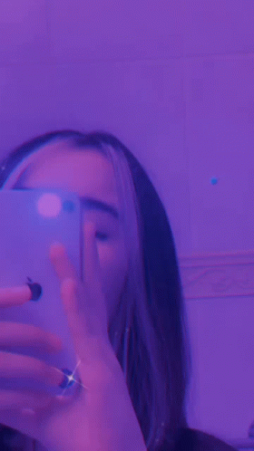 A Close Up Of A Person 'S Face With Purple Lights Behind Her GIF